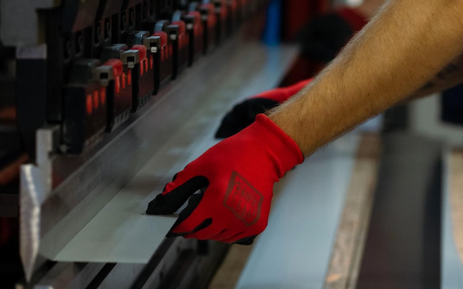 Gloved operator handling sheet stock at a press